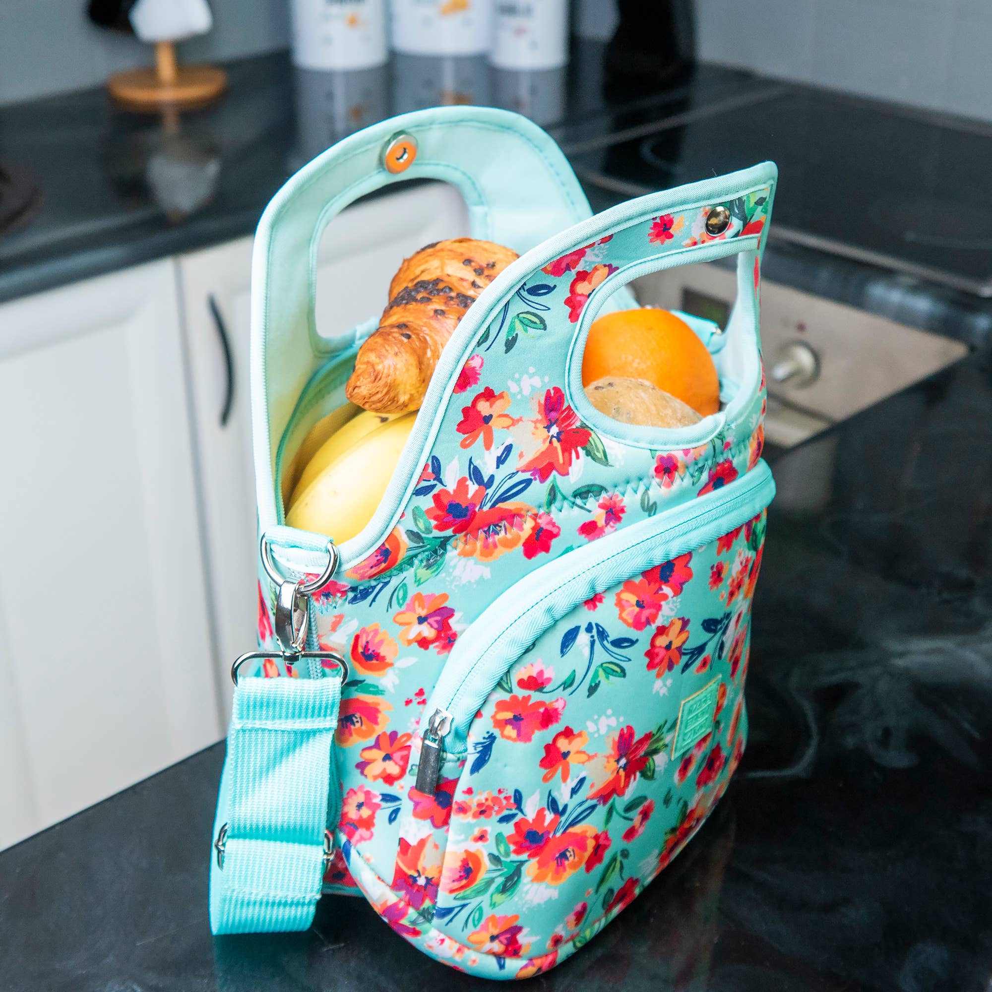 Floral-patterned insulated food bag with fruits on a kitchen counter